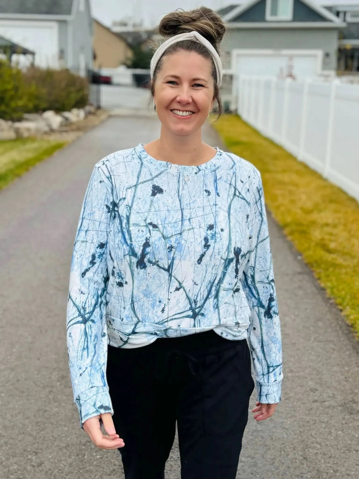 A woman smiles while wearing a long-sleeved shirt with a white and blue cracked ice pattern.