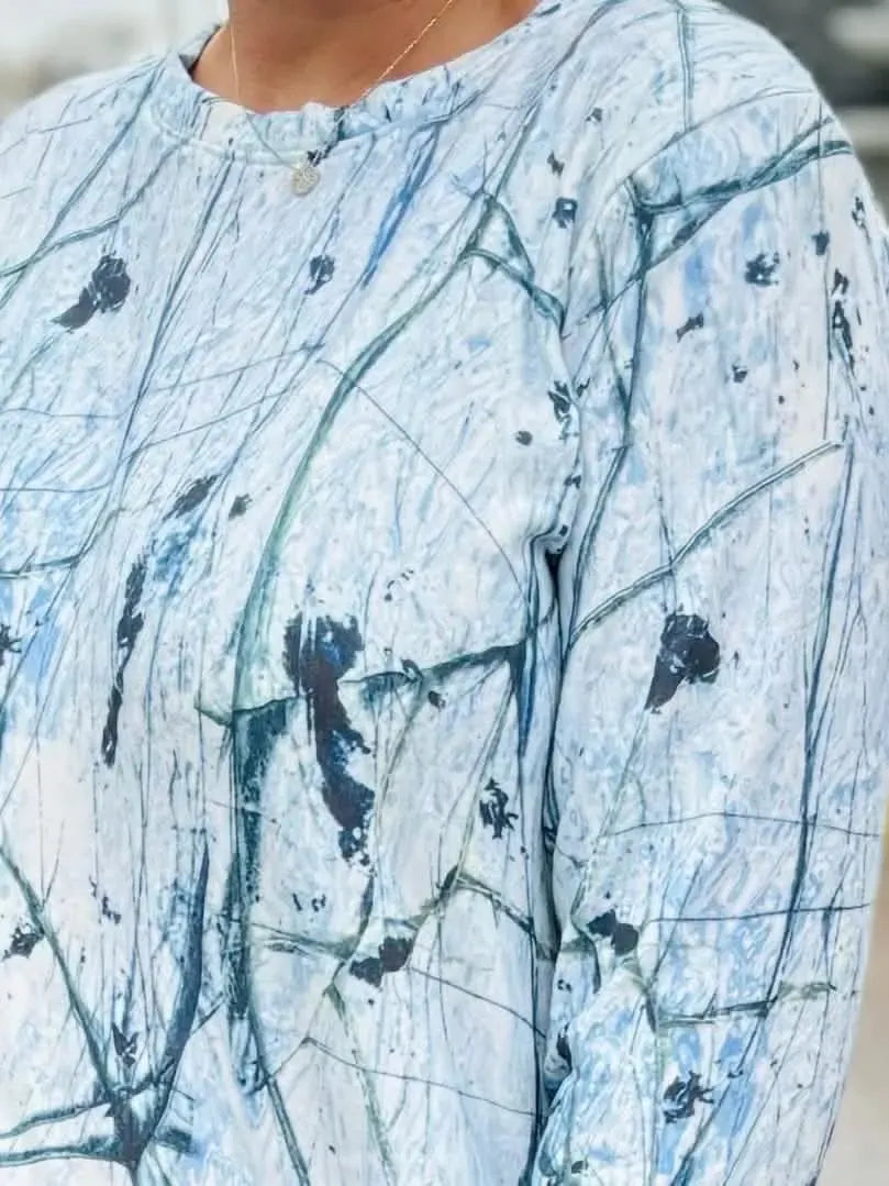 A person wears a long-sleeved shirt with a white and blue cracked ice pattern.