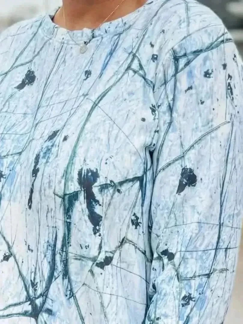 White cracked ice abstract print fabric with green and black veins on a light blue base.