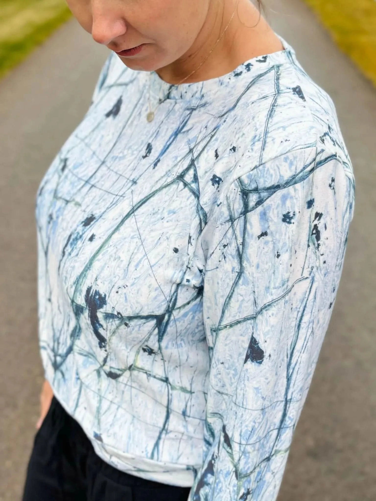 A person wears a white shirt with a blue and black cracked ice pattern.