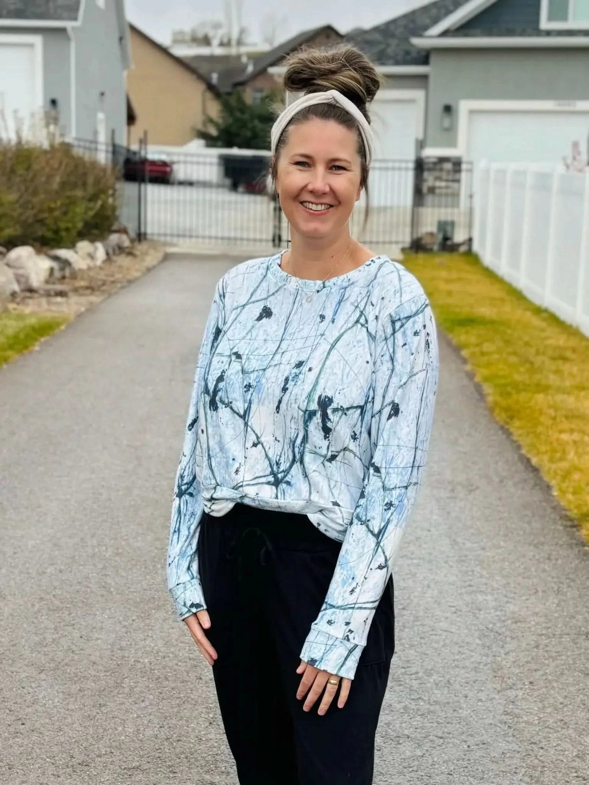 Woman wearing a white and blue cracked ice long-sleeve shirt and black pants.