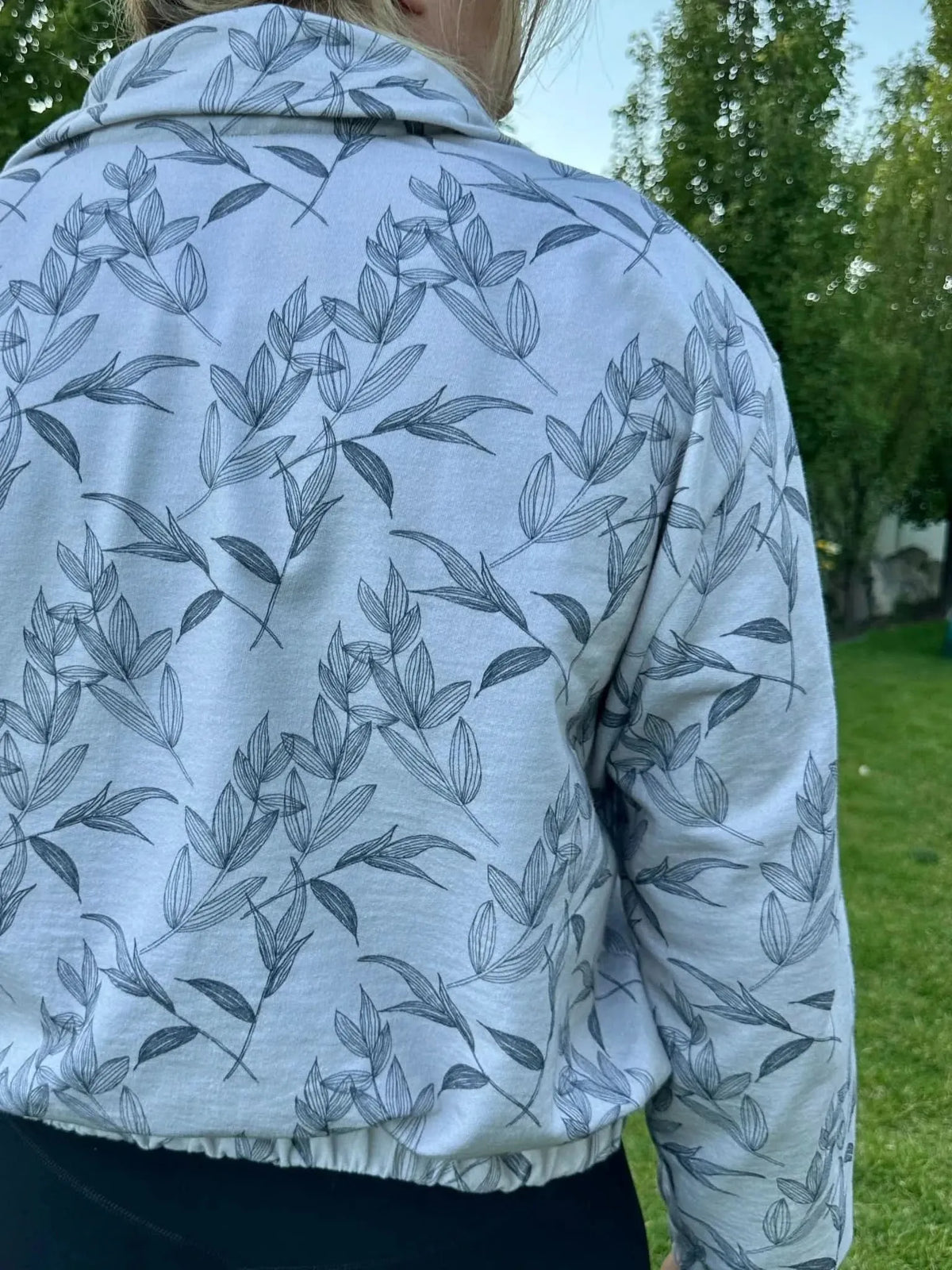 Grey foliage botanical print on white fabric, shown as a back-view collarless jacket.