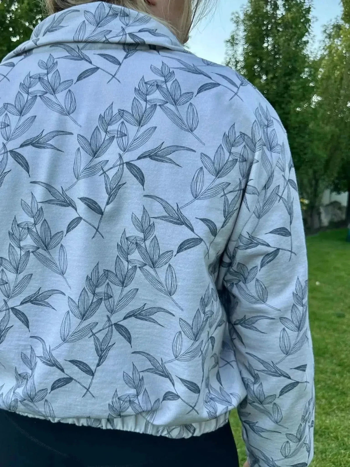 Grey foliage botanical print on white fabric, shown as a back-view collarless jacket.