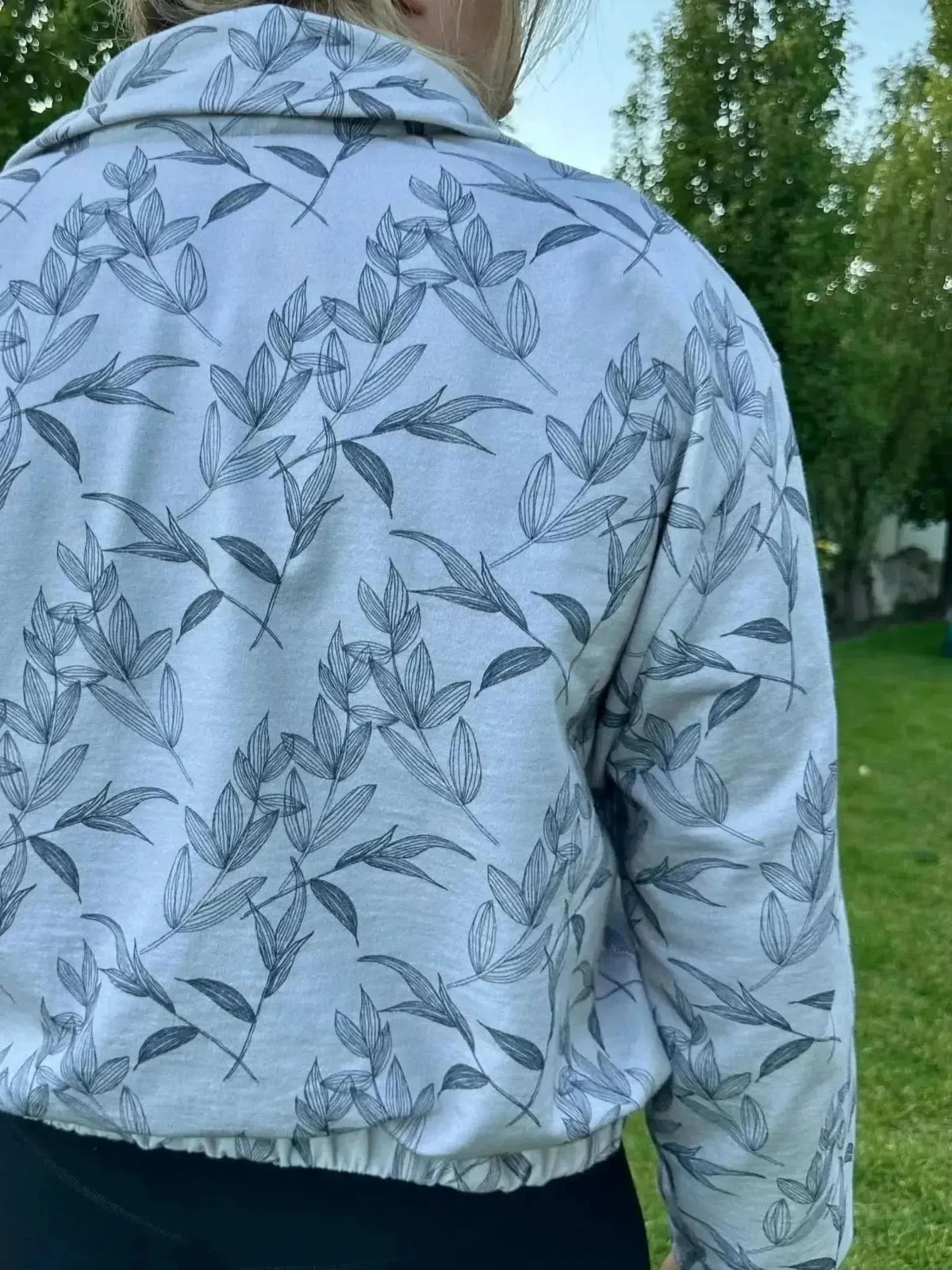 Grey foliage botanical print on white fabric, shown as a back-view collarless jacket.
