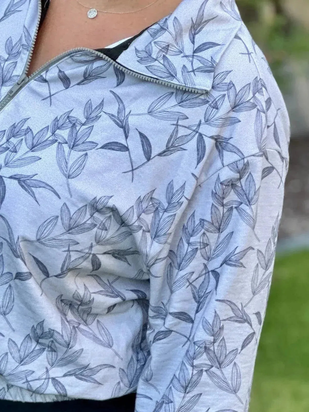 Grey foliage botanical print fabric with leaf patterns on light background.