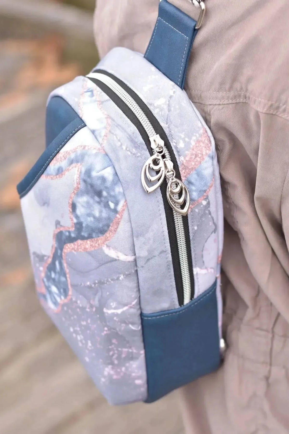 A blue marble patterned bag with a zipper and two decorative pulls.