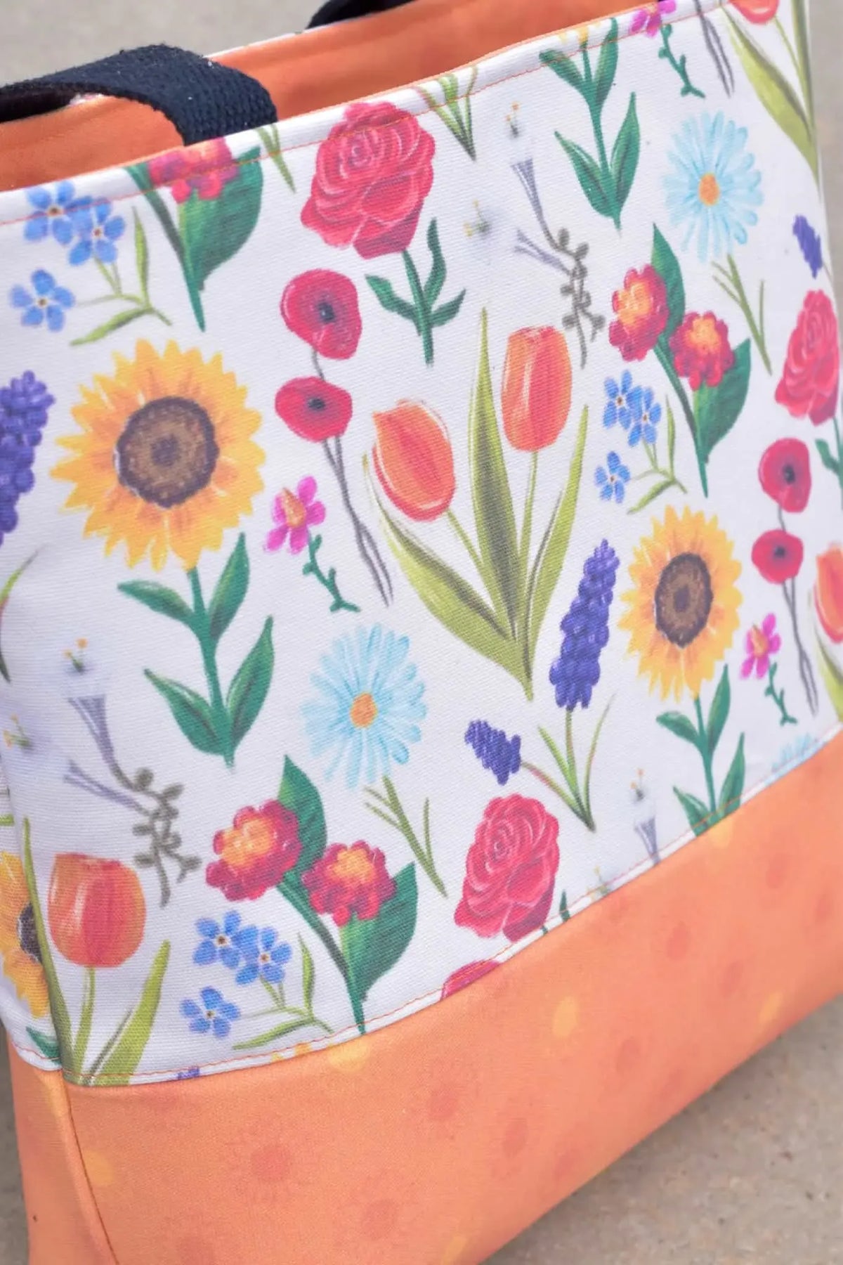 A tote bag with a white floral print and an orange bottom.
