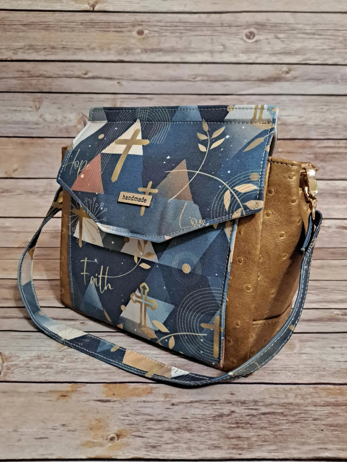 A handmade shoulder bag with a blue, gold, and brown abstract pattern.