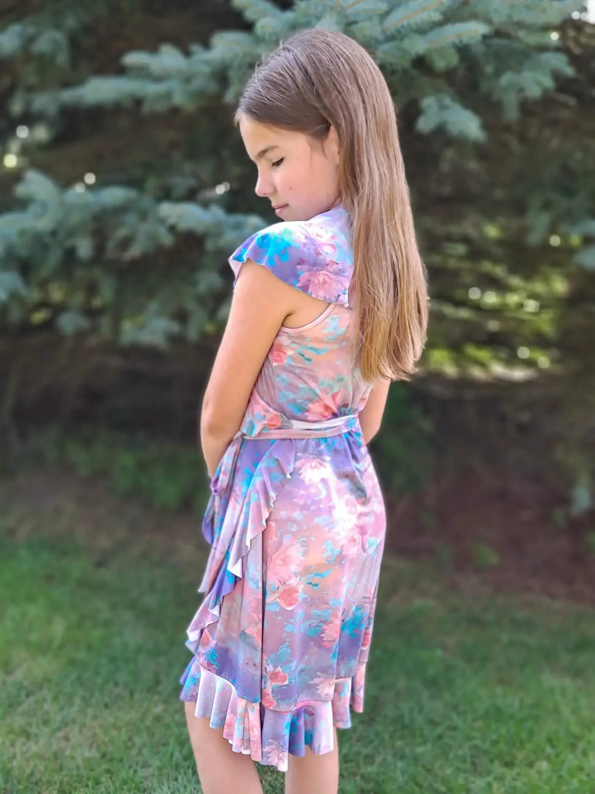 A young girl wearing a purple floral dress with ruffles.