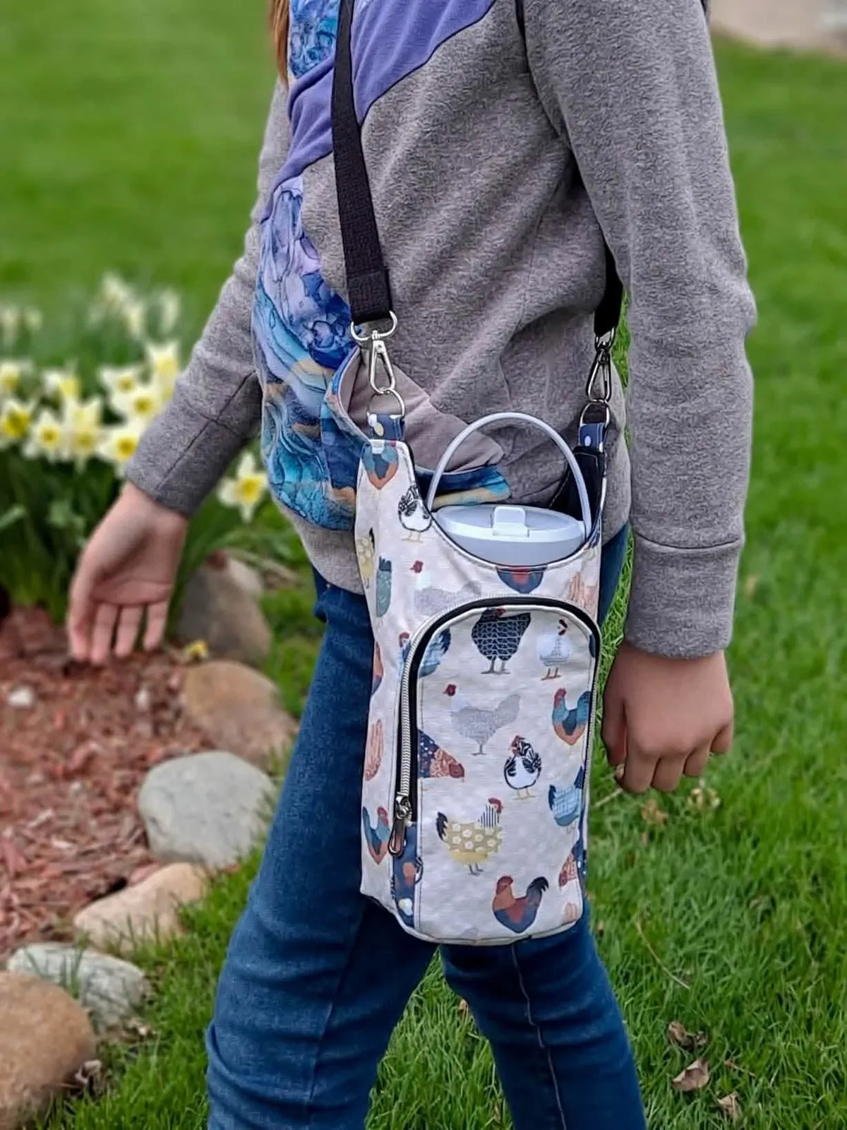 A person walks outdoors carrying a bag with a patchwork chicken print.