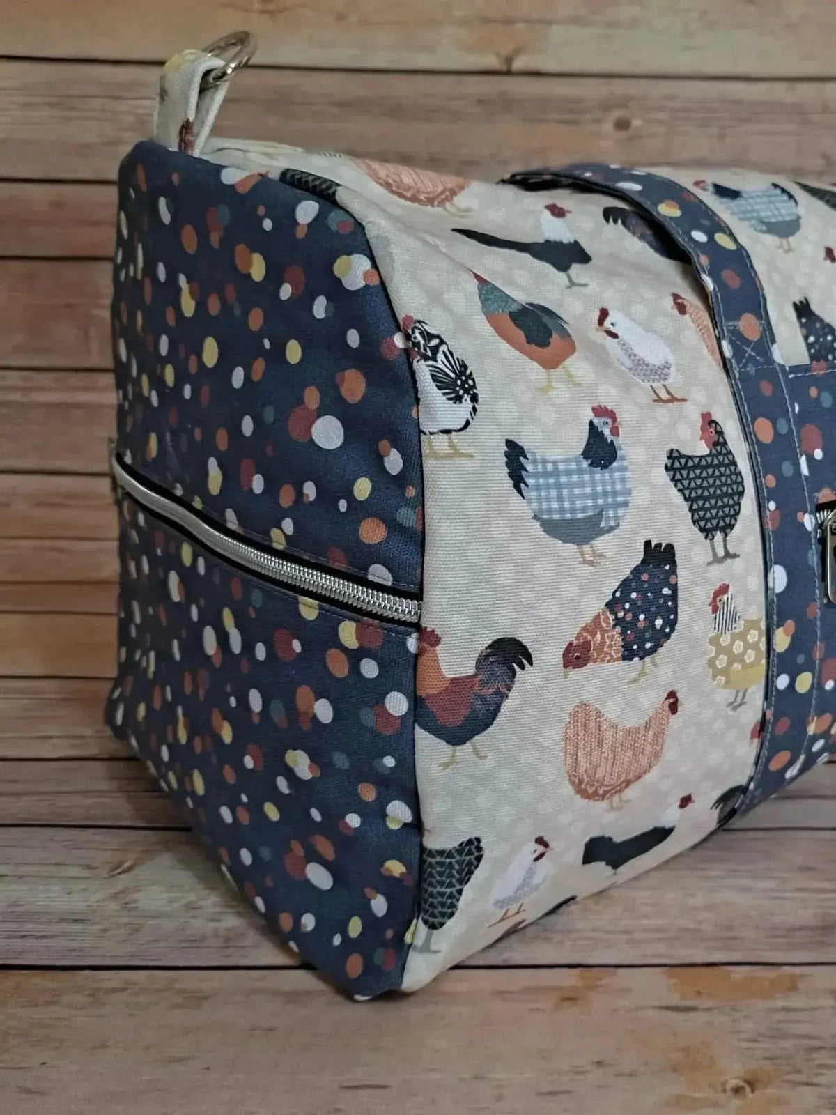 Patchwork fabric with printed chickens and polka dots on a wooden background.
