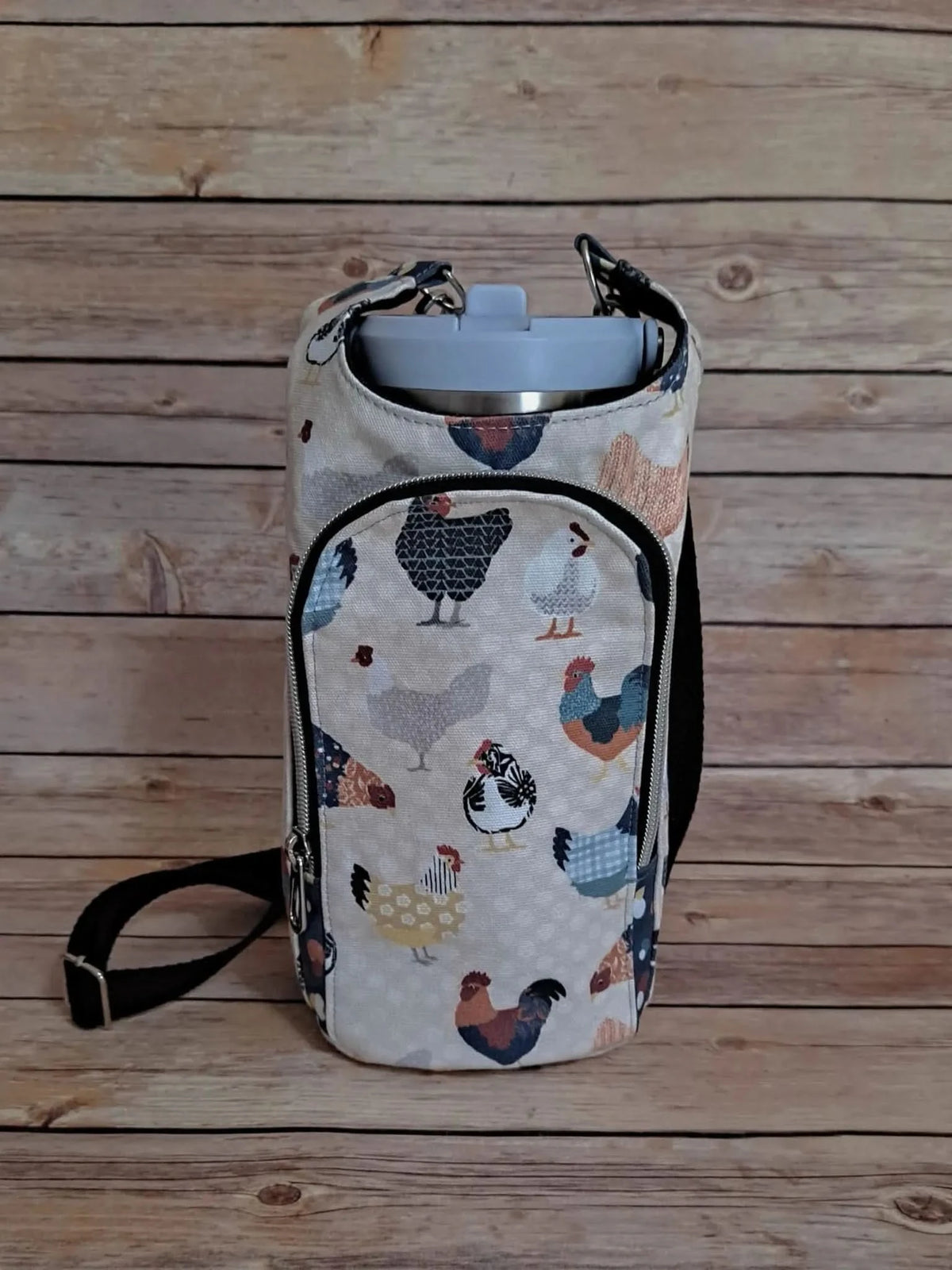 A fabric water bottle holder with a colorful patchwork chicken pattern.