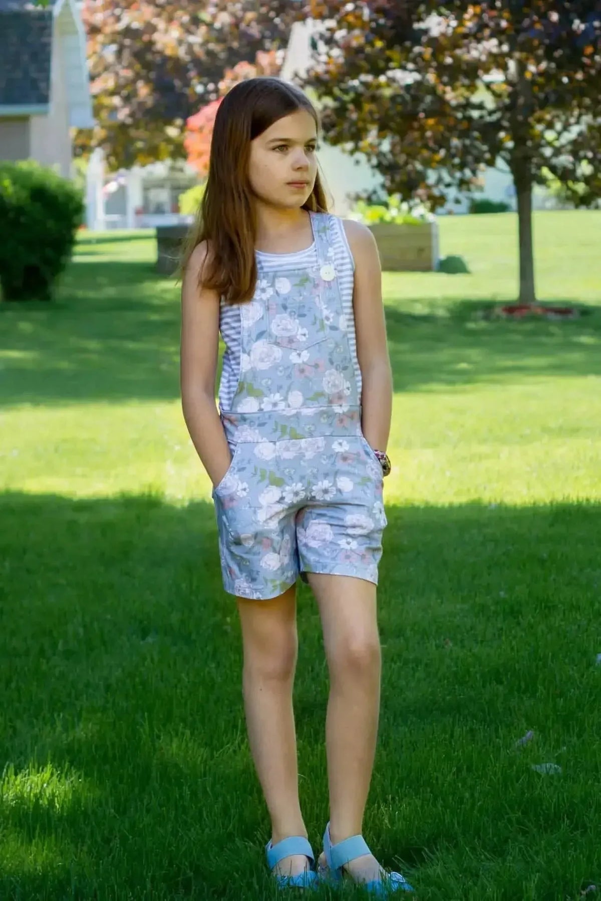 Girl in floral-patterned romper made from dusty blue Japanese fabric, standing on grass.