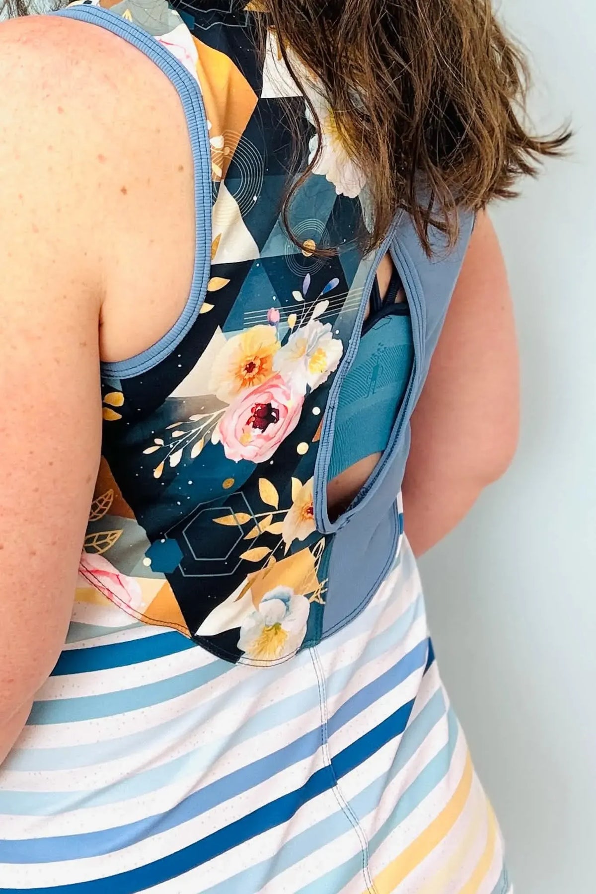 A woman from the back wearing a floral and striped athletic top.