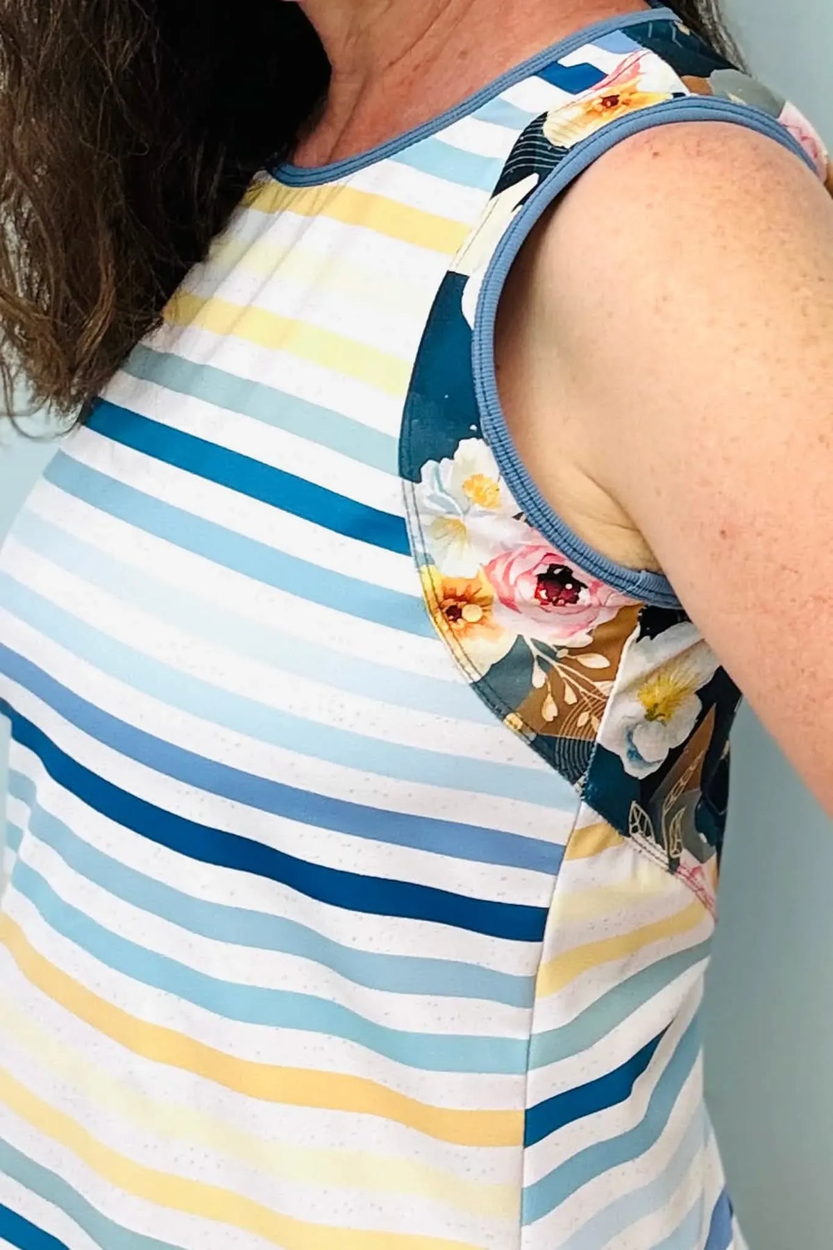 A person wears a striped top with floral accents on the shoulders.