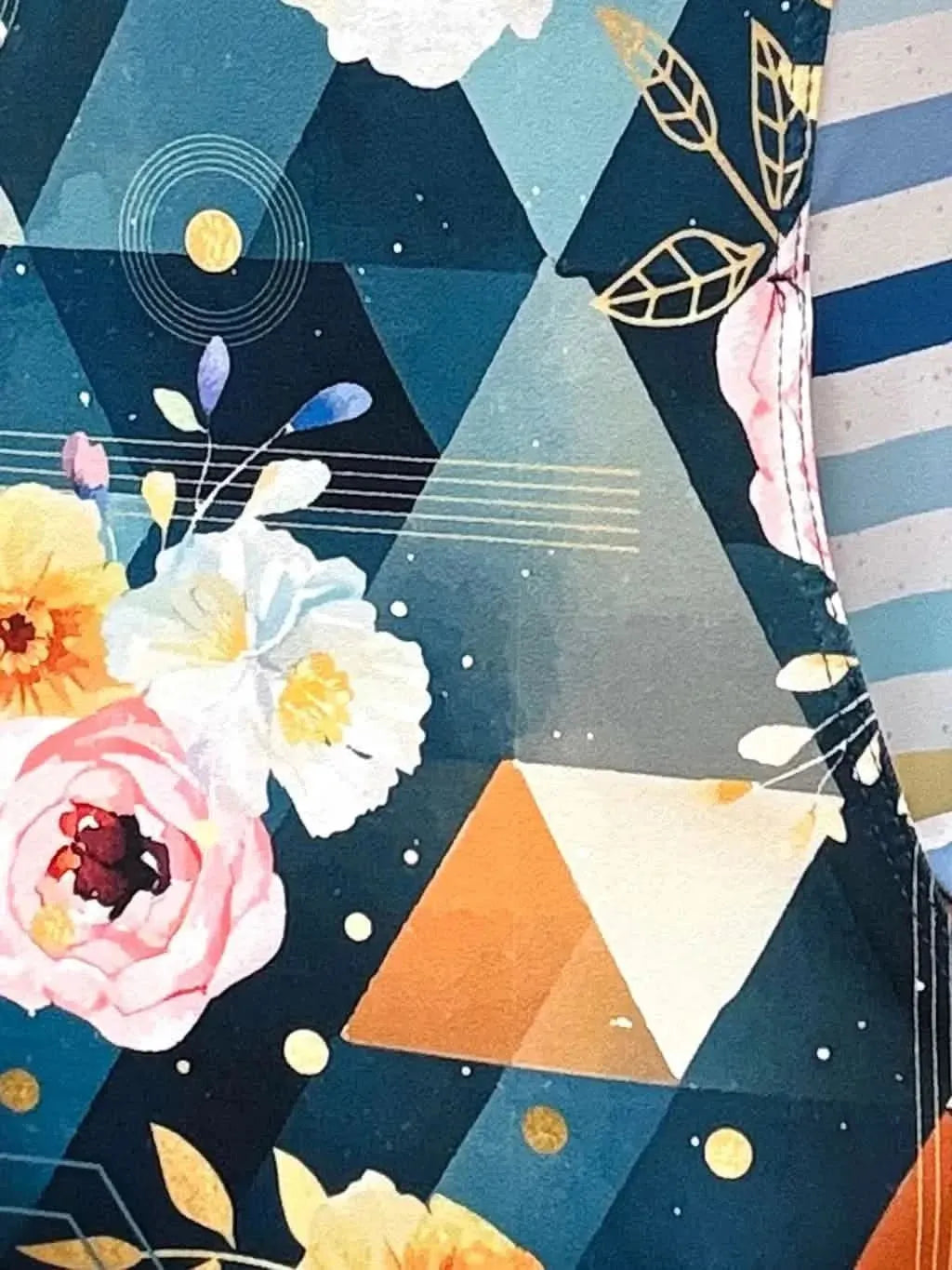 Dark teal geometric floral sewing fabric with triangles, flowers, leaves, and gold accents.