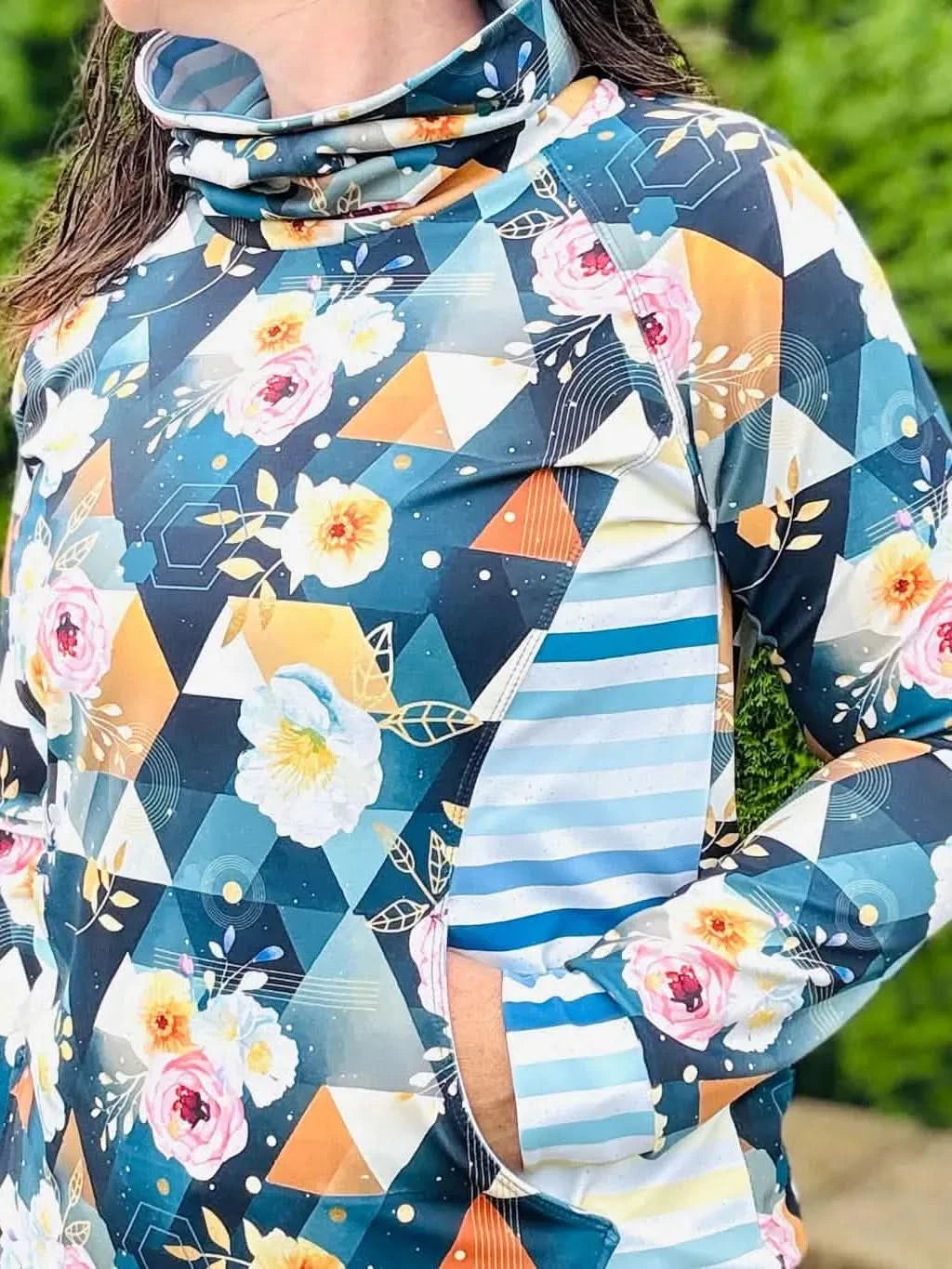 A person wearing a long-sleeved top with a floral and geometric pattern.