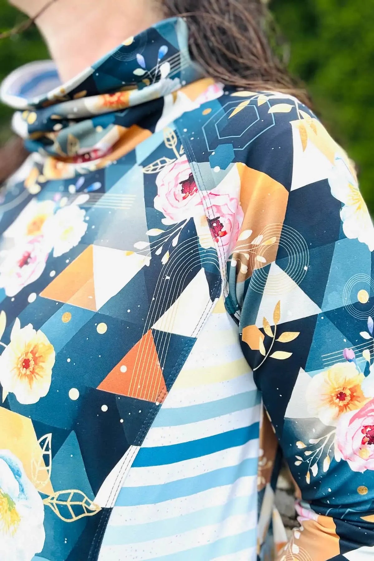A person wears a garment with a floral and geometric pattern in blue, orange, and white.