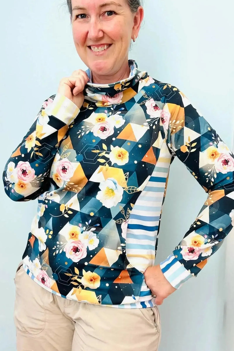 Woman modeling a dark teal geometric floral long-sleeve turtleneck top made from stretch fabric.