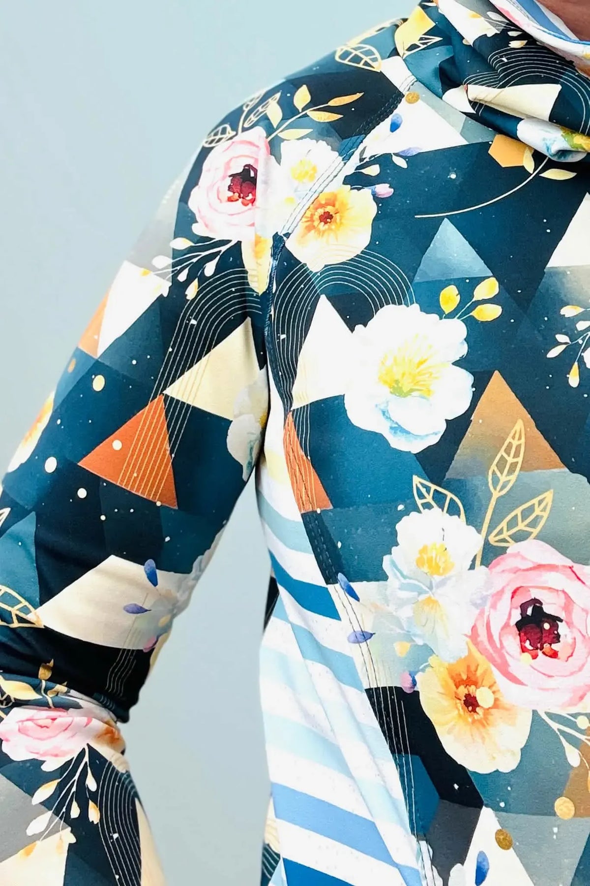 A close-up of a person wearing a floral and geometric patterned long-sleeved shirt.