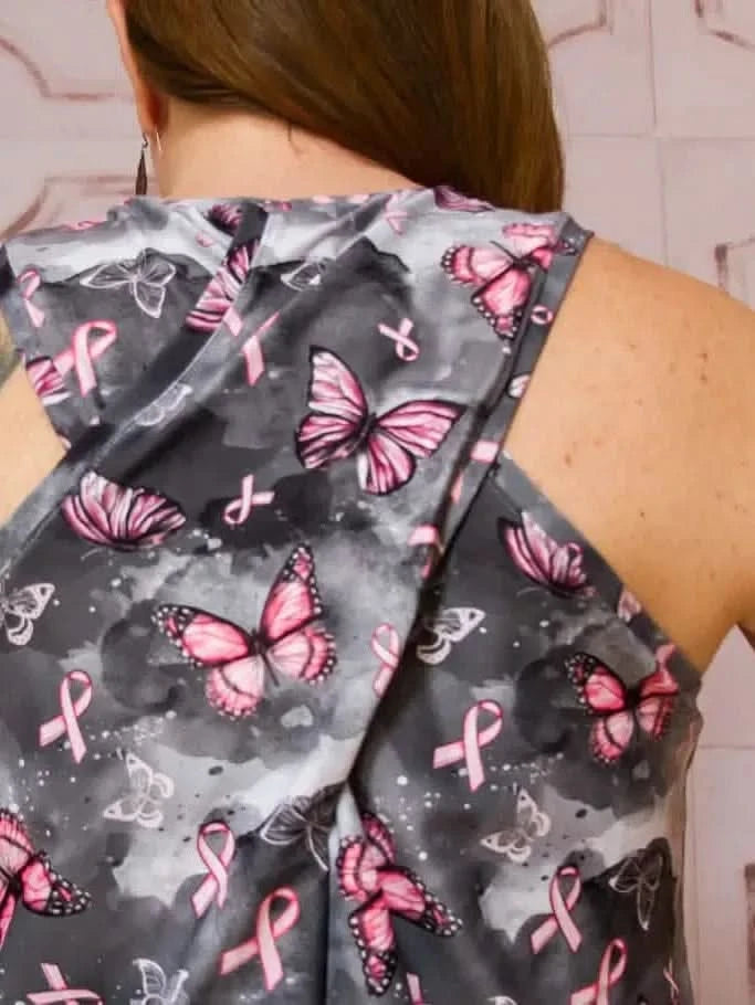 A woman from behind wearing a dark gray top with pink butterflies and ribbons.