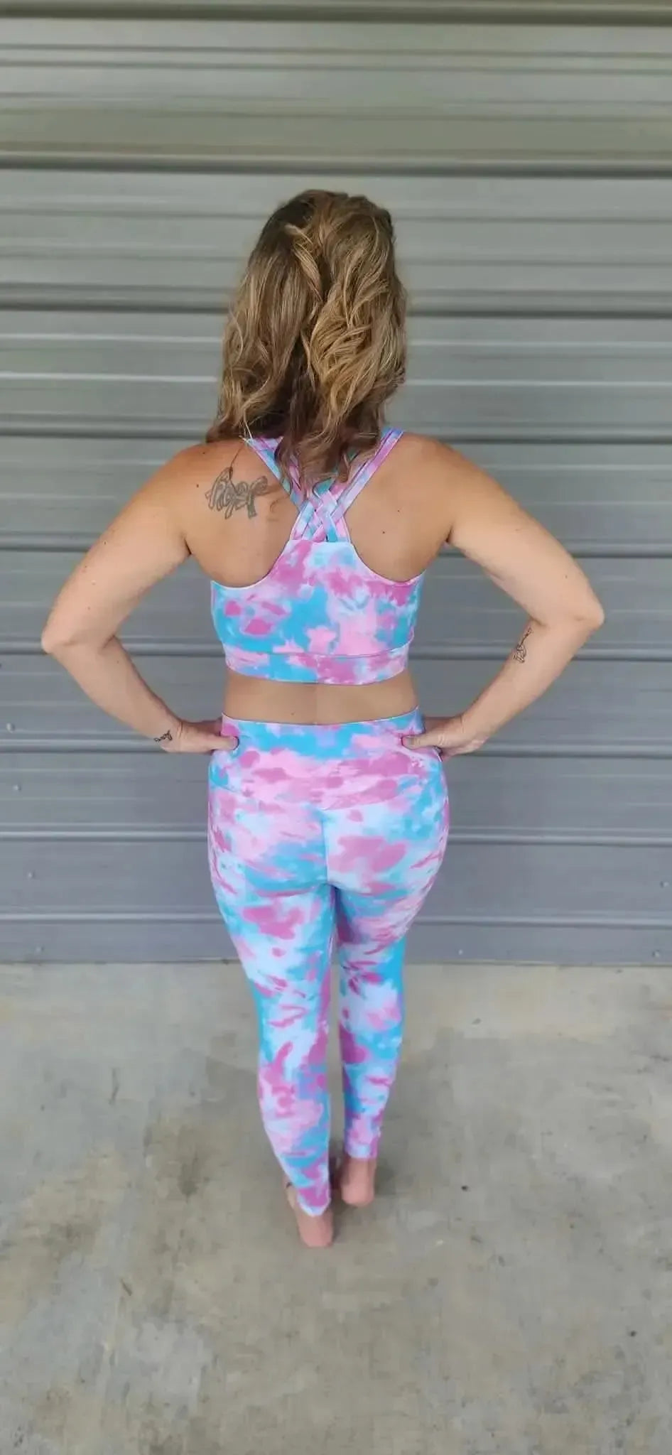 A woman from behind wears a mermaid tie-dye sports bra and leggings set.