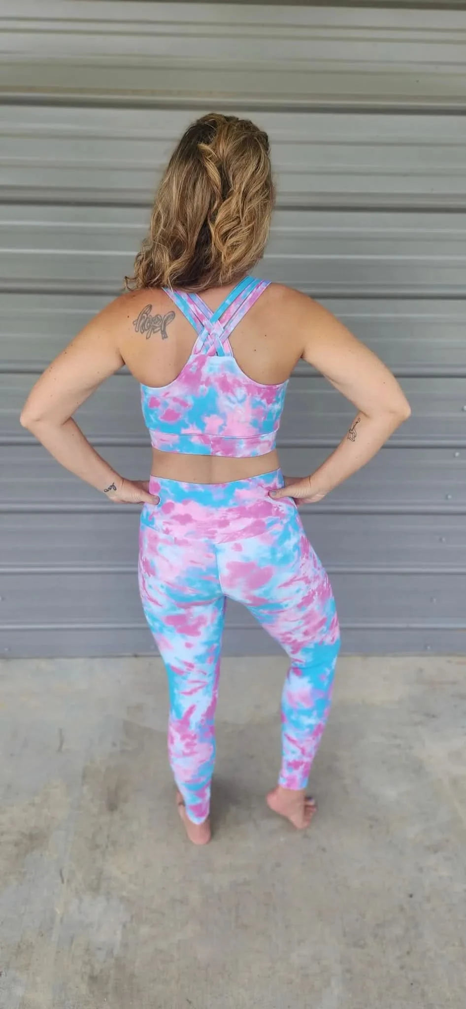 A woman from behind wears a pink and blue tie-dye athletic top and matching leggings.