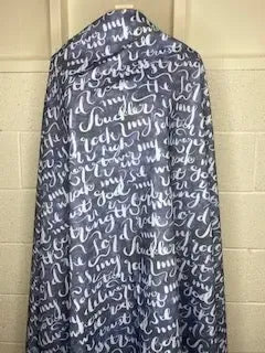 A bolt of dark blue fabric with white handwritten script is draped vertically.