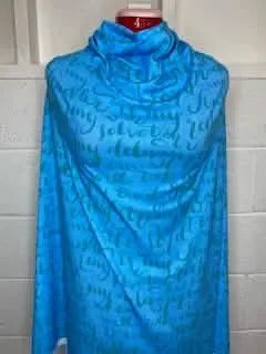 Blue fabric with green script lettering draped over a mannequin.