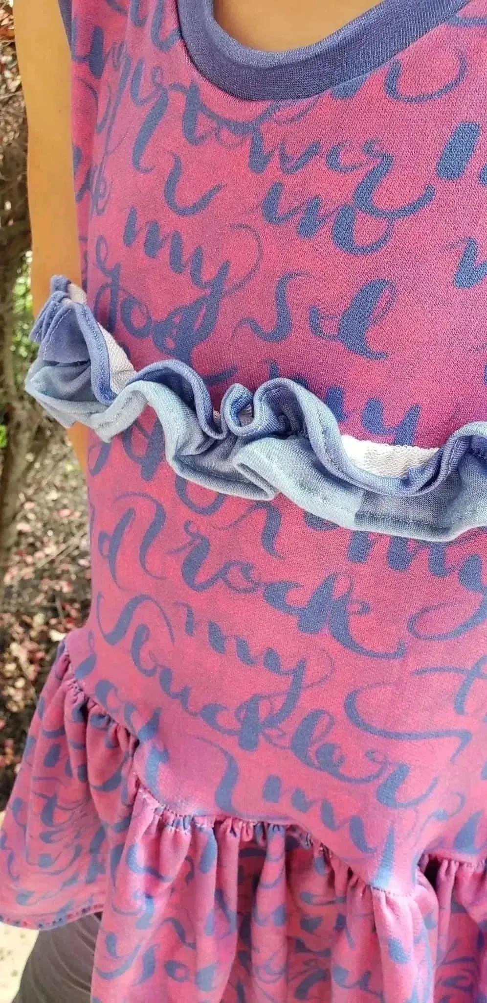 Pink fabric with blue "The Lord is My Rock" Psalm 18:2 verse print and ruffled edges.