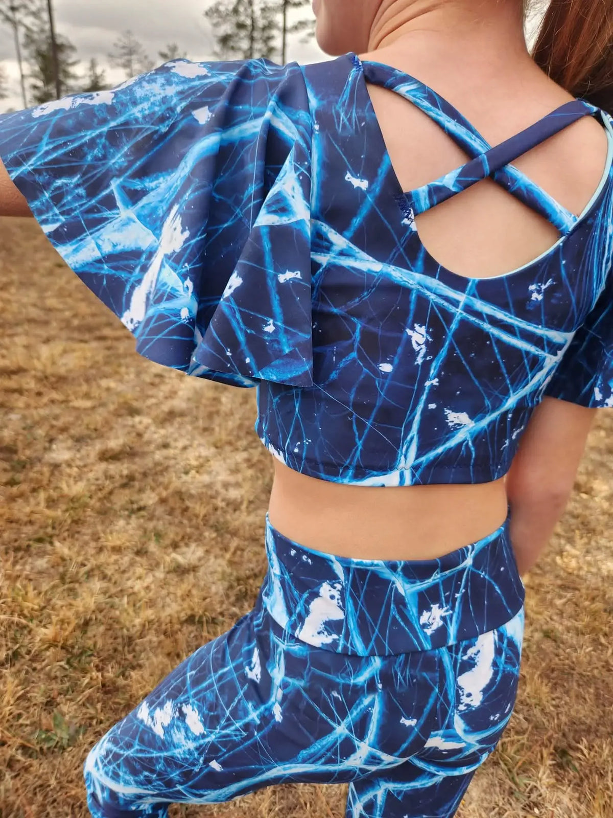 A person models a navy blue athletic top and leggings with a cracked ice pattern.