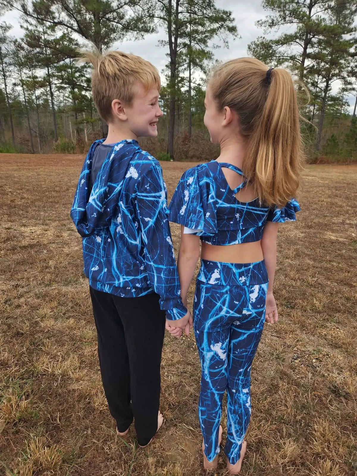 Two children wear matching navy cracked ice print athletic wear.