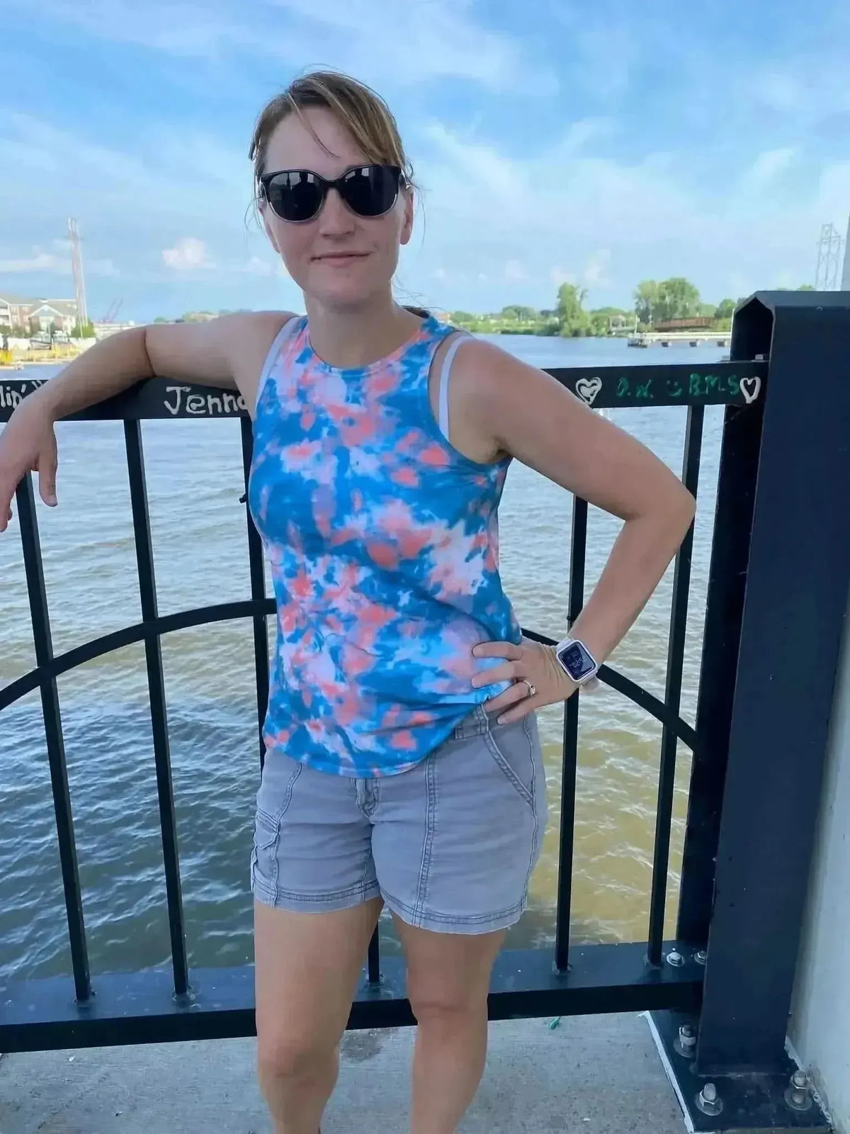 Woman wearing a blue and pink tie-dye tank top with coastal oceanic theme by the water.