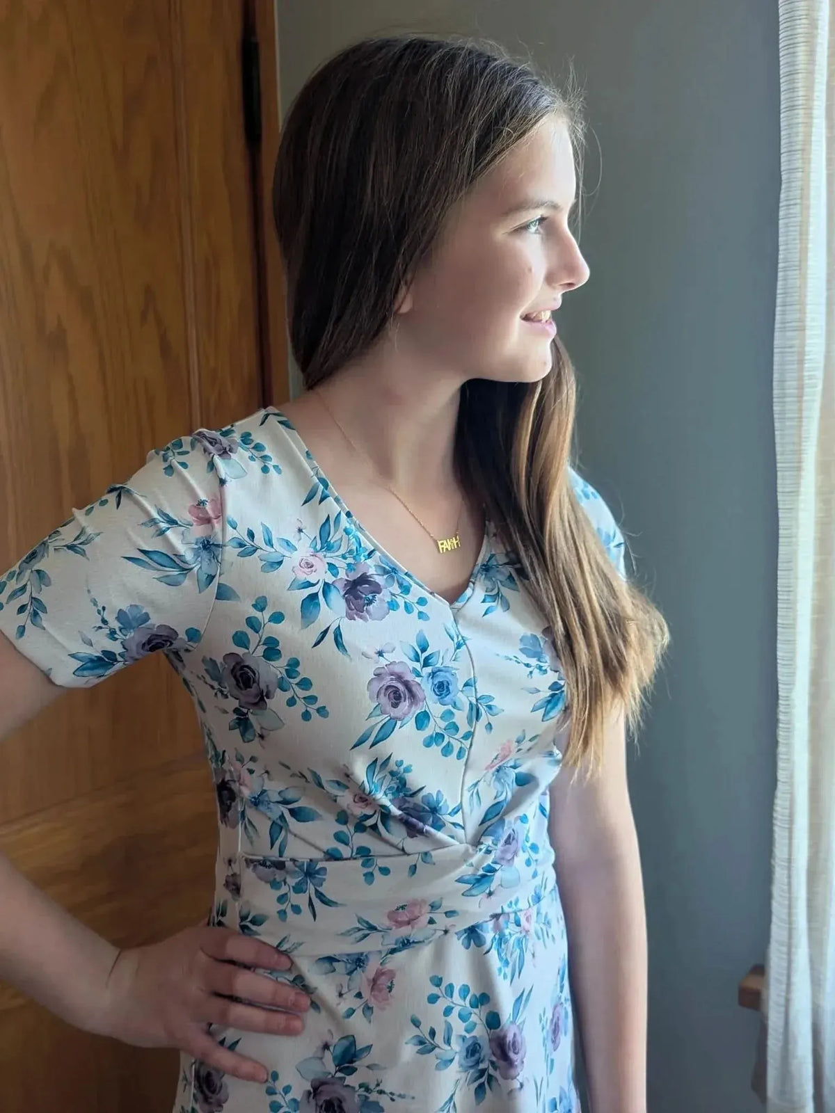 A young girl wears a dress made from blue watercolor floral fabric.