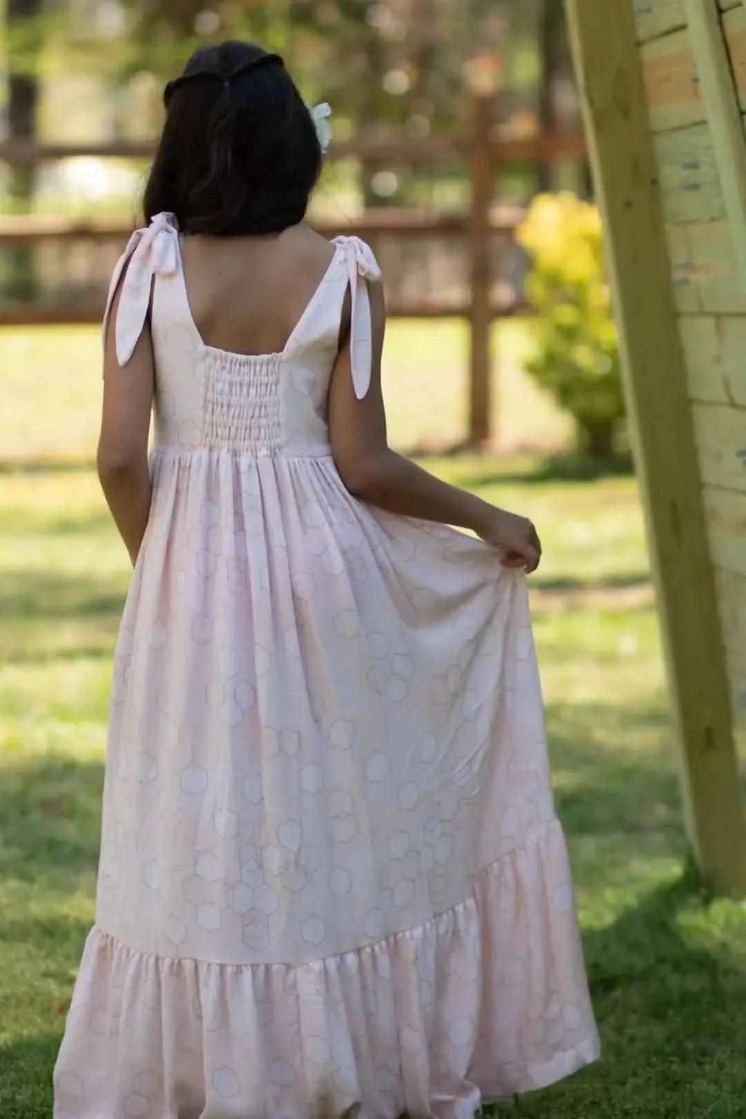 A person from behind wearing a light pink dress with a geometric pattern.