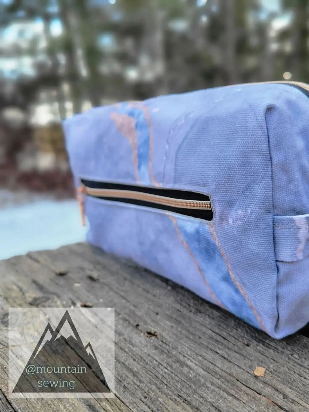 A blue and pink marbled zipper pouch with a black zipper and a side handle.