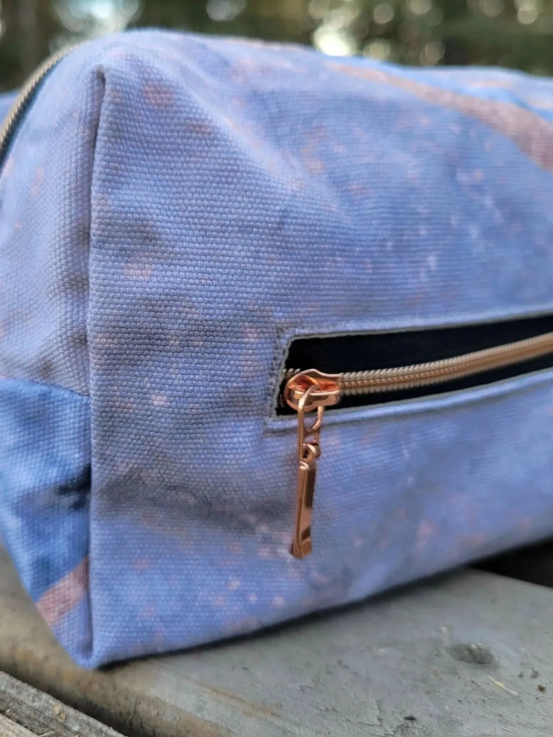 A blue and pink patterned canvas zipper pouch with rose gold zippers.