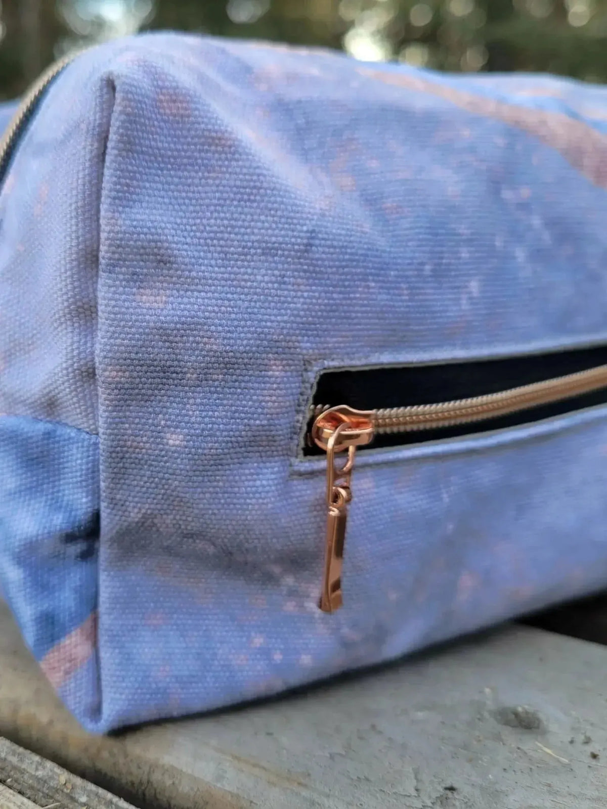 Blue zipper pouch with speckled fabric, black zipper, and copper pull.