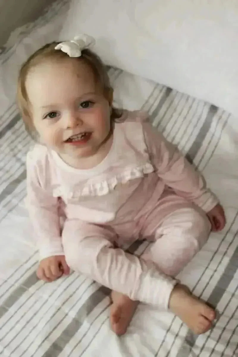 Pink stenciled floral fabric swatch with delicate white flower pattern.