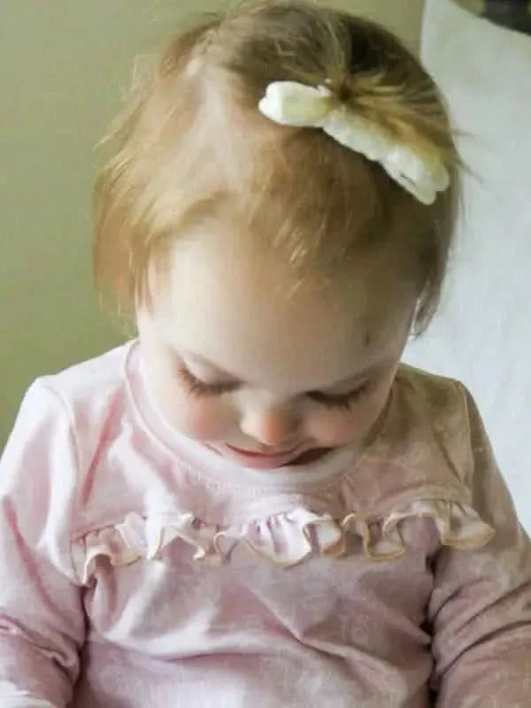 A young child in a pink stenciled floral shirt with ruffles.