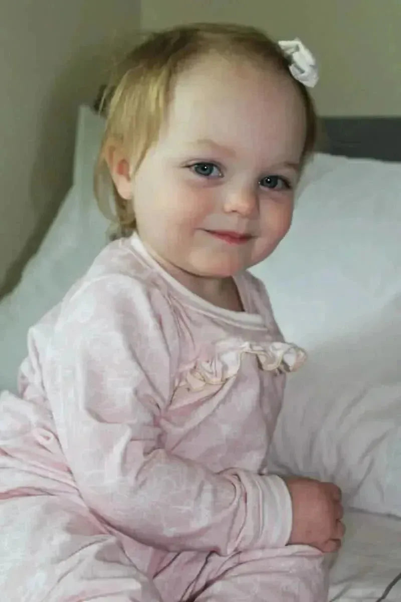 Pink stenciled floral fabric with delicate flower patterns on a light pink background.