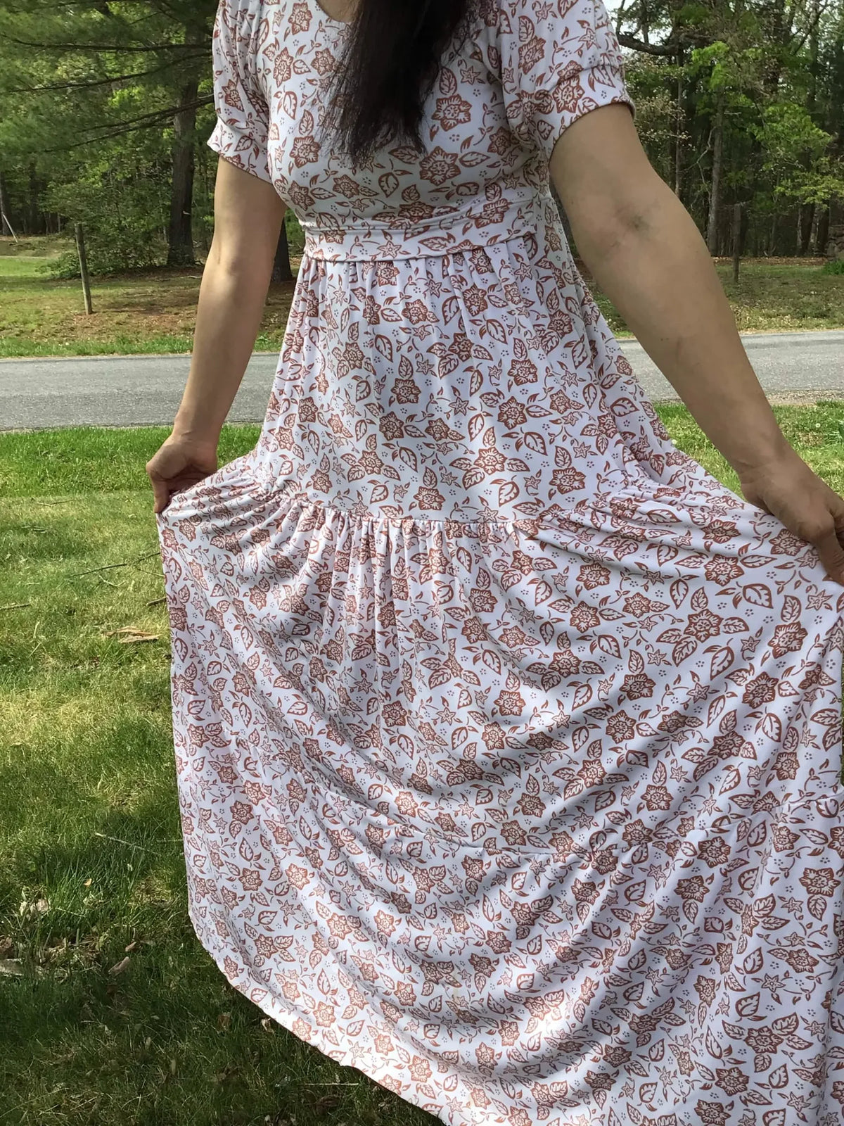 A person in a white dress with a brown folk flower pattern.