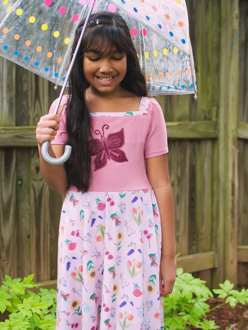 Pink floral fabric with butterfly garden theme, featuring flowers and butterflies.