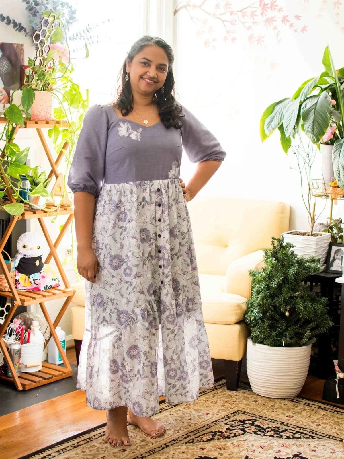 A woman models a long dress with a purple top and a floral skirt.