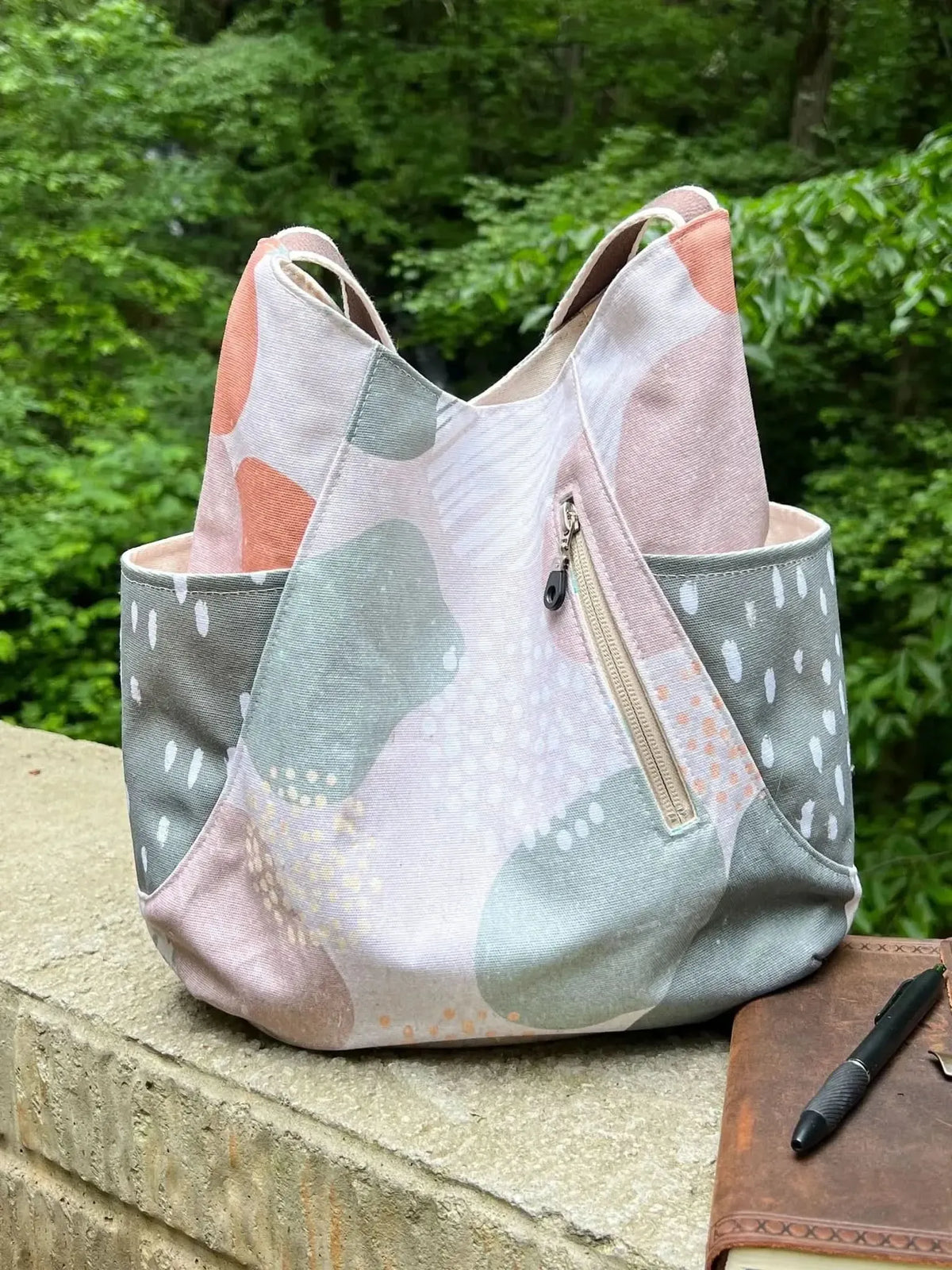 A fabric tote bag with a modern abstract pattern in pink, green, and white.