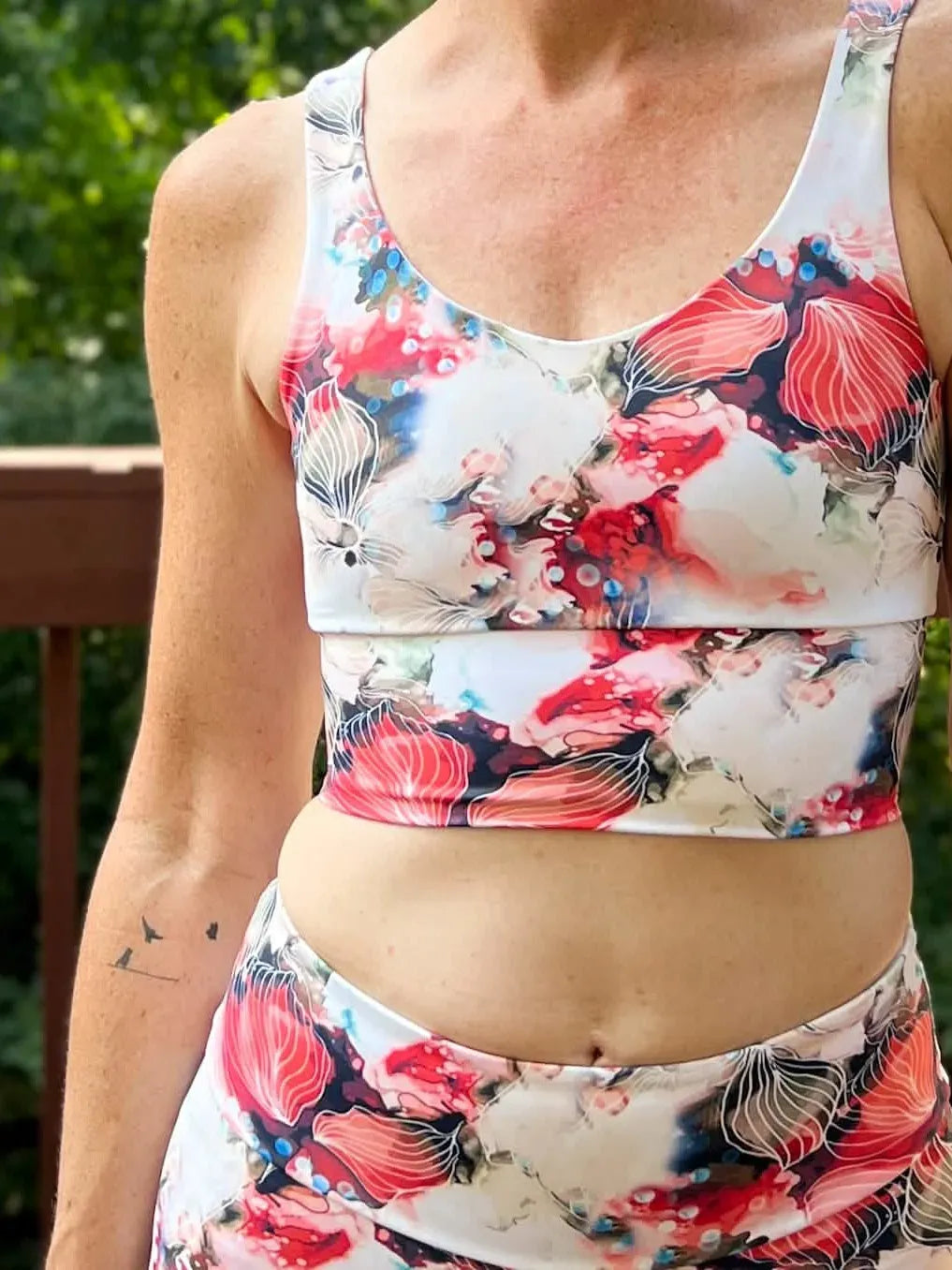 A woman wears a floral print sports bra and matching leggings outdoors.
