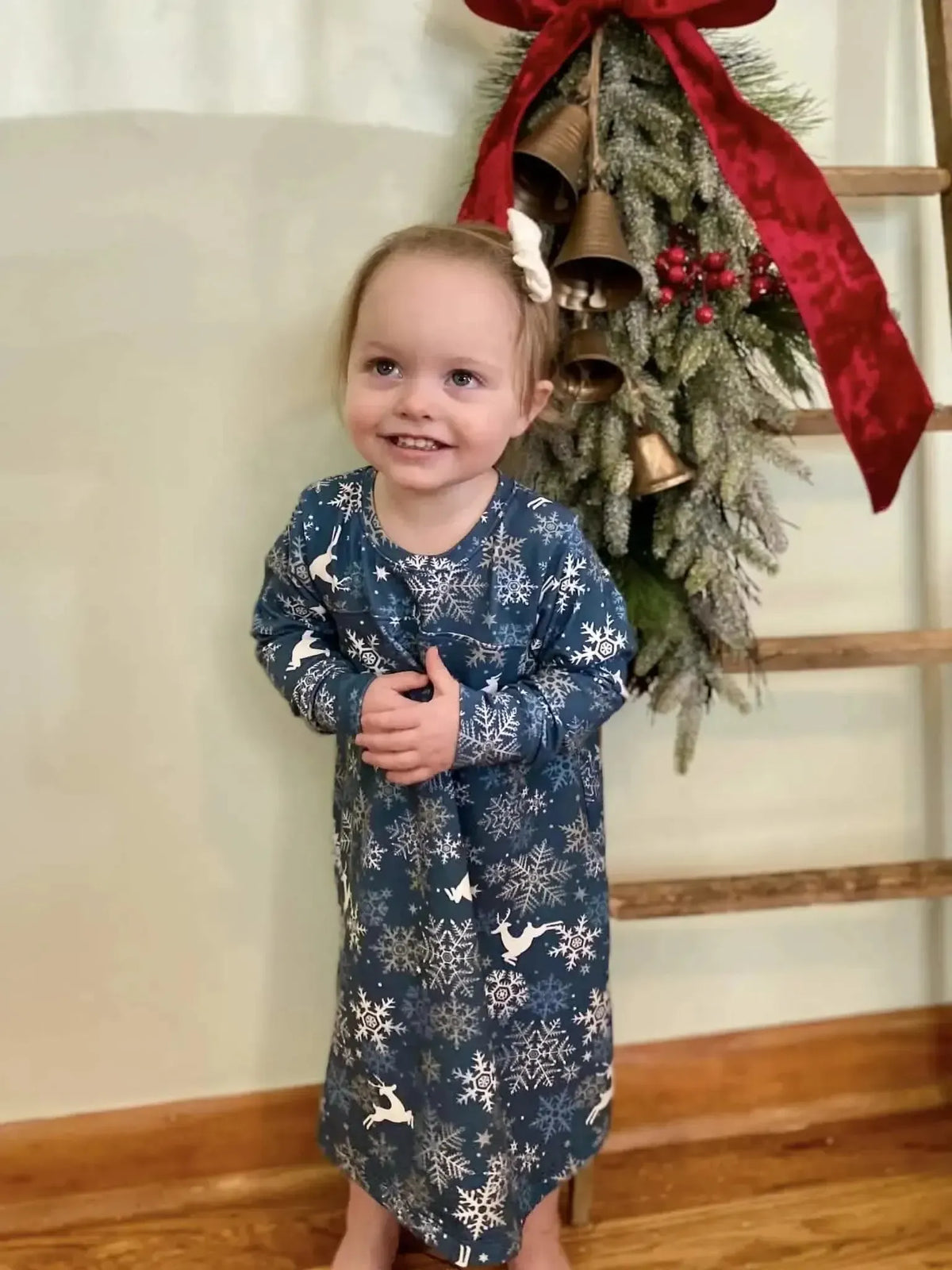 Blue fabric with white snowflakes and reindeer, used in a child's holiday nightgown.