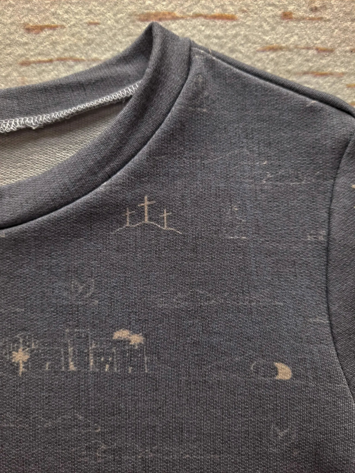 A dark blue fabric with light brown cross designs and other faint patterns.
