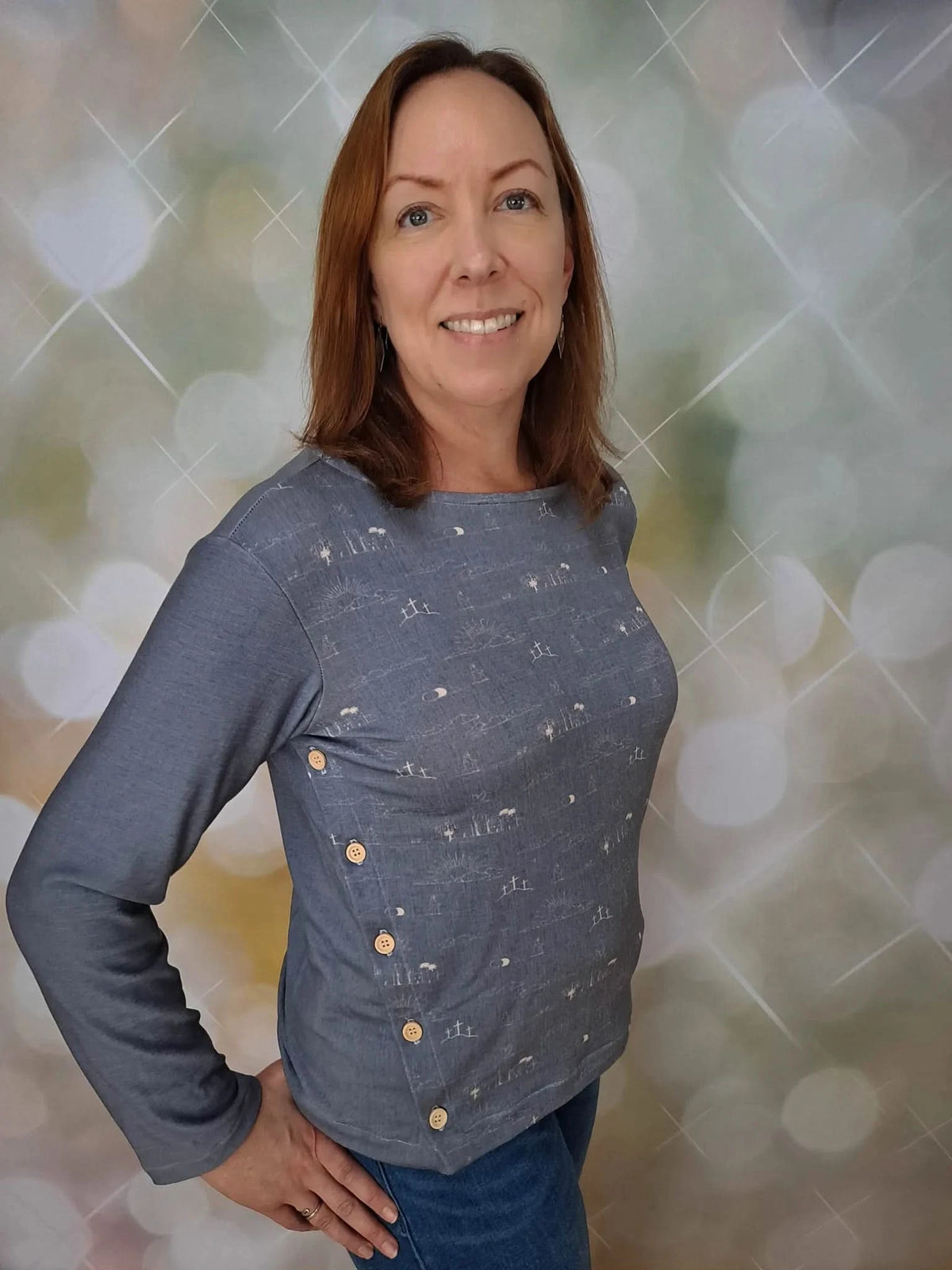 A woman in a blue long-sleeved shirt with a subtle pattern and side buttons.