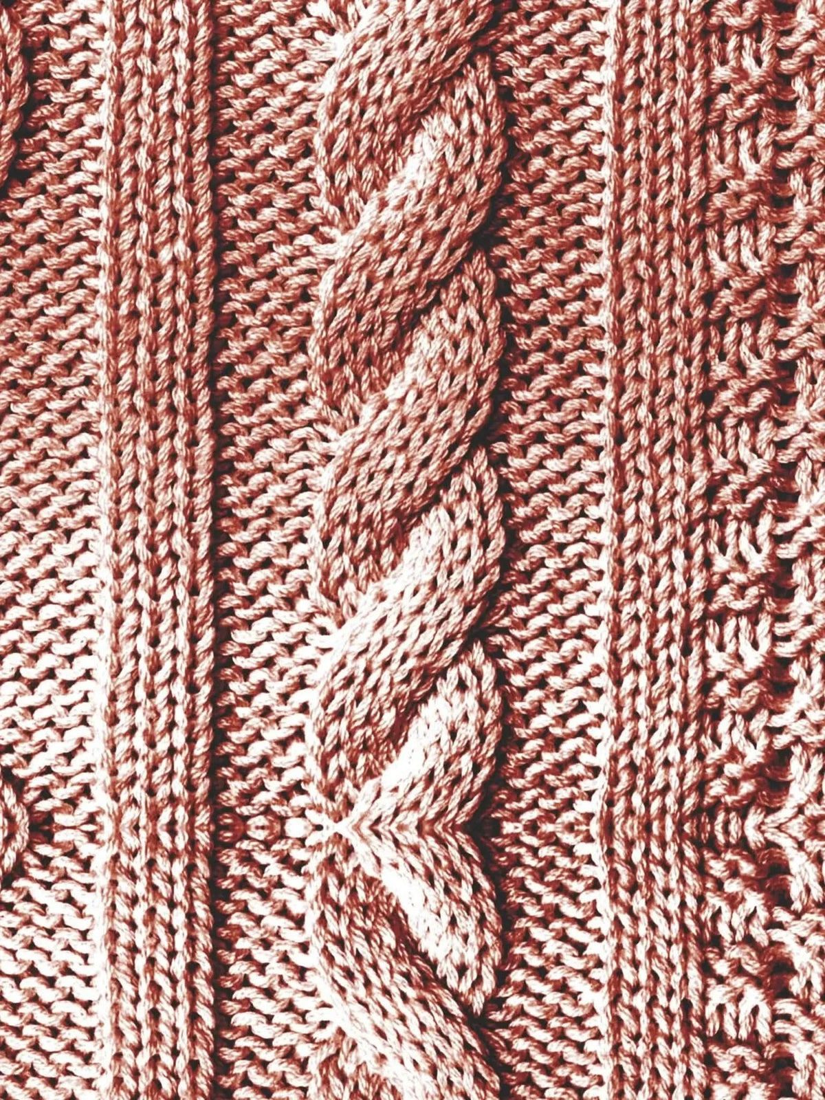 Close-up of a reddish-brown cable knit fabric with various patterns.